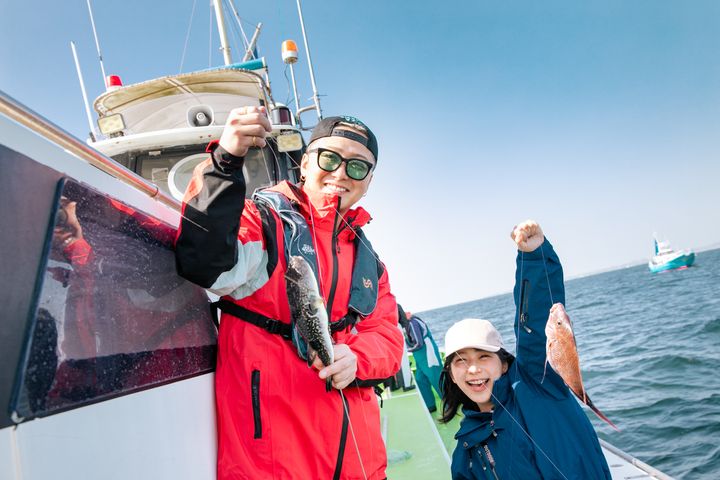 Da-iCE大野雄大さん（左）と第14代アングラーズアイドルの西村美穂さん（右）。大野さんはトラフグ、西村さんは真鯛を釣り上げた。初めて船上で魚を釣り、喜びを隠せない西村さん