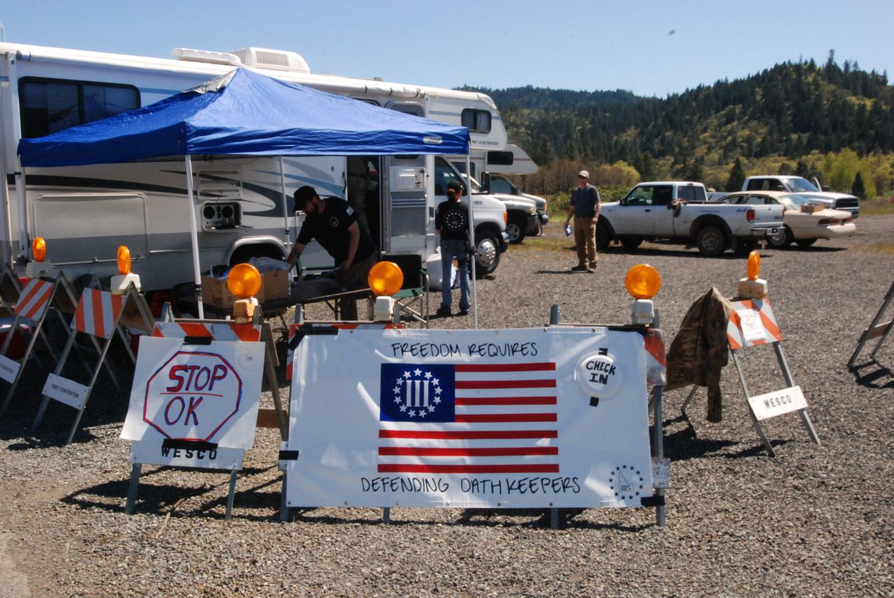 In this April 16, 2015, file photo, people stand ready to check in volunteers at a staging area outside Grants Pass, Oregon, where the local chapter of the constitutional activist group the Oath Keepers was supporting volunteers serving as armed guards for a gold mine on federal land.