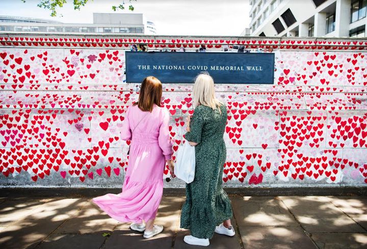 Δύο γυναίκες στέκονται μπροστά από το Εθνικό Μνημείο COVID στο Λονδίνο, κοιτάζοντας τις καρδιές που έχουν ζωγραφιστεί στη μνήμη όσων πέθαναν από την COVID-19. Πάνω από 150.000 χειροποίητες καρδιές αποτελούν τραγική μαρτυρία για τις ζωές που χάθηκαν από αυτόν τον ιό.