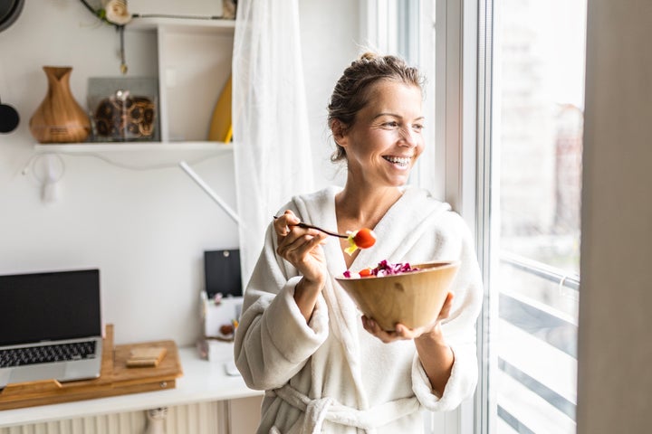 Beautiful young woman eating healthy vegetable salad wearing bathrobe