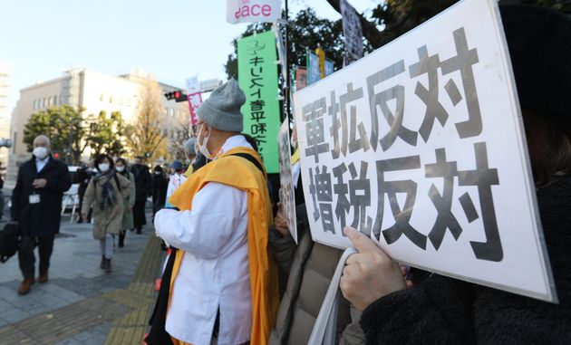 安全保障関連3文書改定に反対し、「軍拡反対」などと書かれたプラカードを掲げるデモ参加者＝2022年12月16日、東京・永田町