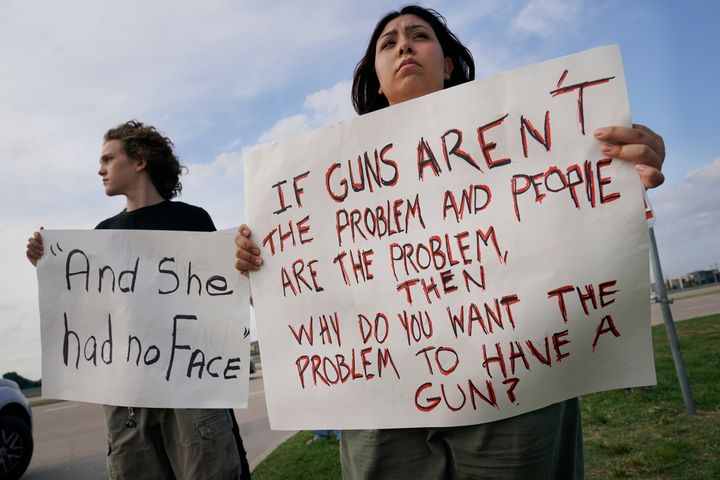 Two teenagers hold protest signs outside a prayer vigil after a mass shooting in Allen, Texas, on May 6. The sign on the left appears to reference a man having said that <a href="https://www.huffpost.com/entry/allen-premium-outlets-shooting-responder_n_6457c59ee4b0ff22e37b21c2" target="_blank" role="link" class=" js-entry-link cet-internal-link" data-vars-item-name="he found a girl without a face" data-vars-item-type="text" data-vars-unit-name="645be957e4b0c10612e92328" data-vars-unit-type="buzz_body" data-vars-target-content-id="https://www.huffpost.com/entry/allen-premium-outlets-shooting-responder_n_6457c59ee4b0ff22e37b21c2" data-vars-target-content-type="buzz" data-vars-type="web_internal_link" data-vars-subunit-name="article_body" data-vars-subunit-type="component" data-vars-position-in-subunit="46">he found a girl without a face</a> while attempting to aid the shooting victims.