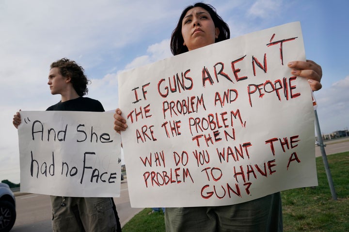 Two teenagers hold protest signs outside a prayer vigil after a mass shooting in Allen, Texas, on May 6. The sign on the left appears to reference a man having said that <a href="https://www.huffpost.com/entry/allen-premium-outlets-shooting-responder_n_6457c59ee4b0ff22e37b21c2" target="_blank" role="link" class=" js-entry-link cet-internal-link" data-vars-item-name="he found a girl without a face" data-vars-item-type="text" data-vars-unit-name="645be957e4b0c10612e92328" data-vars-unit-type="buzz_body" data-vars-target-content-id="https://www.huffpost.com/entry/allen-premium-outlets-shooting-responder_n_6457c59ee4b0ff22e37b21c2" data-vars-target-content-type="buzz" data-vars-type="web_internal_link" data-vars-subunit-name="article_body" data-vars-subunit-type="component" data-vars-position-in-subunit="46">he found a girl without a face</a> while attempting to aid the shooting victims.