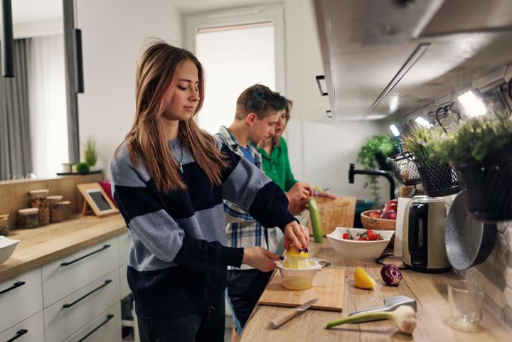 Generation Z teenage kids making vegetable salad. The girl is making lemon juice and the boy is peeling a cucumberShot with Canon R5