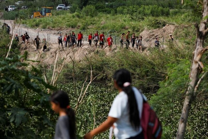 Migrants walk along the banks of the Rio Bravo river after crossing the border to turn themselves in to U.S. Border Patrol agents before the lifting of Title 42, as seen from Matamoros, Mexico, on May 11.