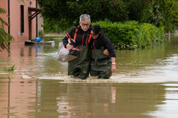 A couple walk through a flooded road of Lugo, Italy, May 18, 2023.