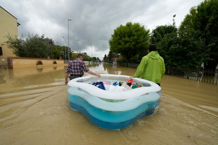 People use a plastic portable pool to carrie bags and personal effects in a flooded road of Lugo, Italy, May 18, 2023. 