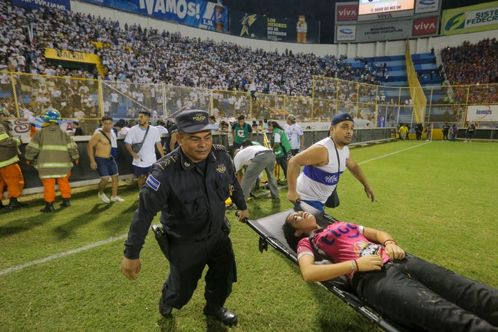 An injured fan is carried on the field of Cuscatlán Stadium in San Salvador, El Salvador, on Saturday. At least 12 people were killed and dozens more injured when stampeding fans pushed through one of the access gates at the quarterfinal soccer match between Alianza and FAS.