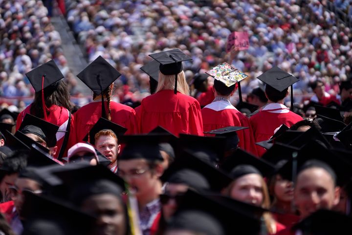 Graduates stand with their backs to the podium as David Zaslav, president and CEO of Warner Bros.  Discovery, speaking at Boston University's commencement ceremonies on Sunday.
