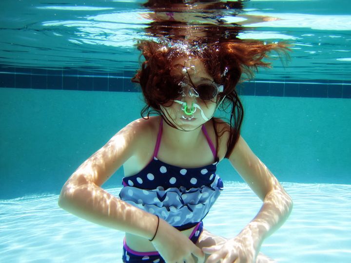 Close up underwater view of elementary age girl swimming in swimming pool in Florida