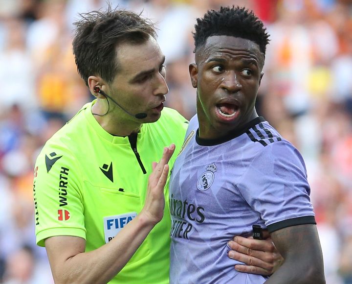 Referee Ricardo De Burgos Bengoetxea, left, speaks with Real Madrid's Vinicius Junior during a Spanish La Liga soccer match between Valencia and Real Madrid, at the Mestalla stadium in Valencia, Spain, Sunday, May 21, 2023. The game was temporarily stopped when Vinicius said a fan had insulted him from the stands. He was later sent off after clashing with Valencia players. (AP Photo/Alberto Saiz)