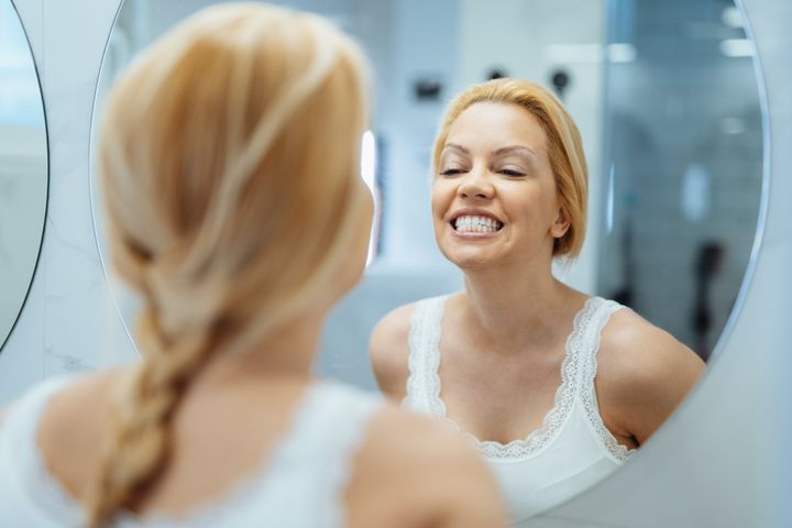 Naturally beautiful mature woman in front of the mirror in the bathroom
