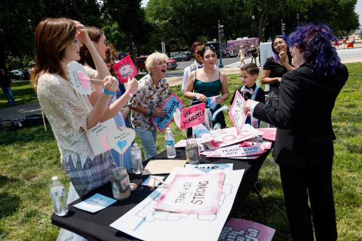 Kids pick out signs to have their picture taken at a photo booth during the Trans Youth Prom.