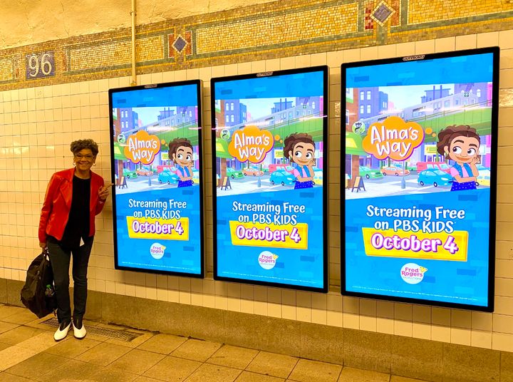 The author next to an ad for "Alma's Way" in a New York City subway station.