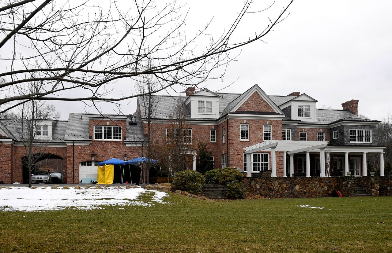 A yellow tarp is set up and watched over by a police officer outside of the garage to Fotis Dulos' home on Jan. 28, 2020, in Farmington, Connecticut.
