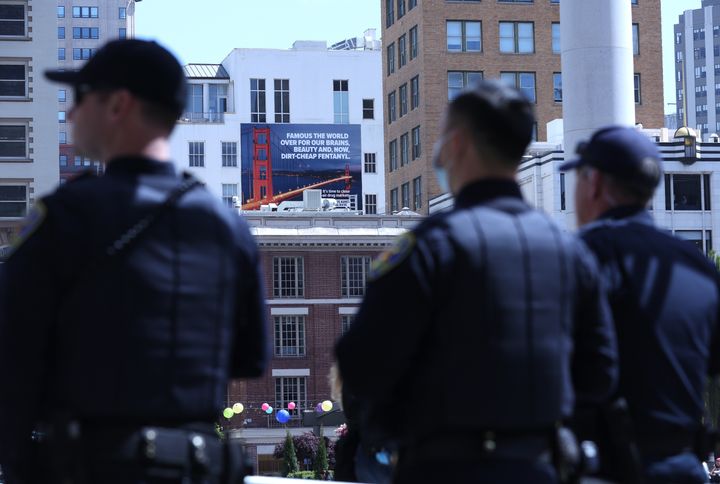 San Francisco police officers look on in April of last year near a controversial billboard that warns against fentanyl.