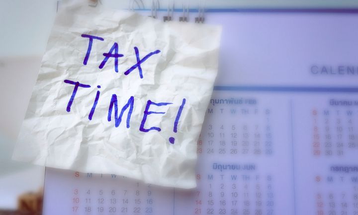 Tax time concept; Tax Time word be written on the white paper note with a calendar.