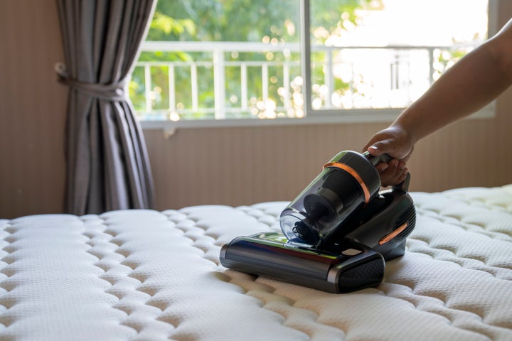 Cropped view of man removing dust on mattress with vacuum cleaner