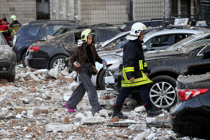 A rescuer escorts a girl outside a multi-storey residential building, partially destroyed after night drone attacks in Kyiv on May 30, 2023.
