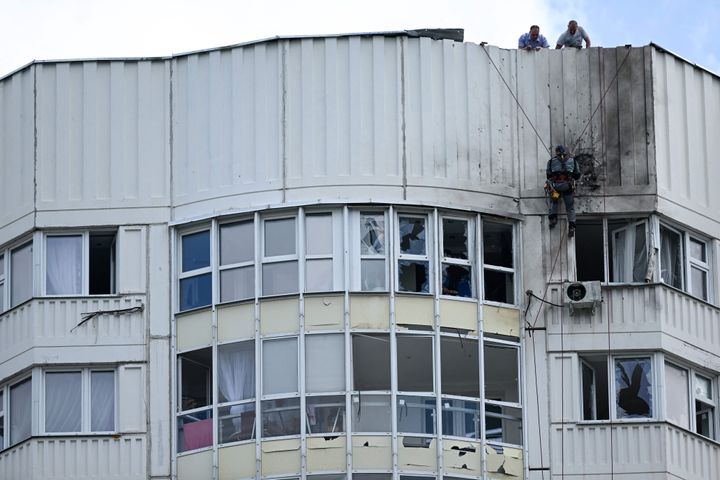 Seorang spesialis memeriksa bagian depan gedung apartemen bertingkat yang rusak setelah dilaporkan adanya serangan pesawat tak berawak di Moskow.