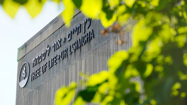 The signage on the dormant landmark Tree of Life synagogue in Pittsburgh's Squirrel Hill neighborhood is framed in spring foliage on April 19, 2023.