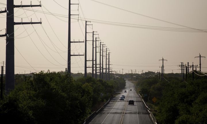 Vehicles run on a road next to power transmission lines in San Antonio on July 18, 2022.