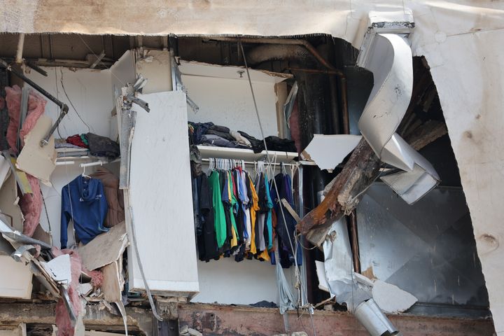Des vêtements sont toujours suspendus dans un placard après l'effondrement d'une partie du bâtiment.