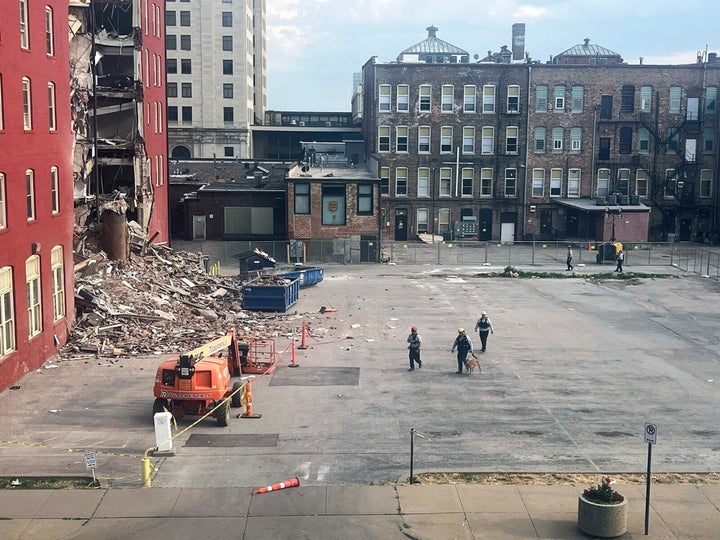 Three search and rescue workers and a dog approach the site of a building collapse in Davenport, Iowa, during a search, Thursday, June 1, 2023. (Grace Kinnicutt/Quad City Times via AP)
