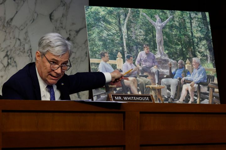 Sen. Sheldon Whitehouse (D-R.I.) displays a copy of a painting commissioned by Harlan Crow that features Justice Clarence Thomas and Crow alongside other conservative leaders at a private retreat.