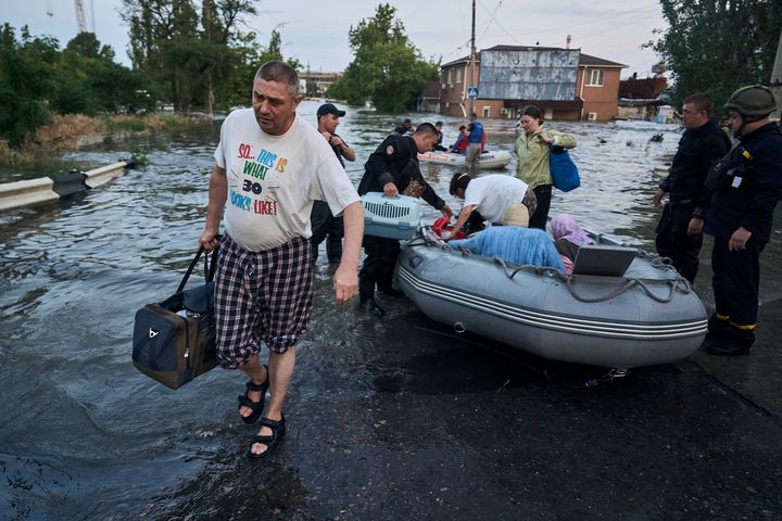 Rescue workers attempt to tow boats carrying residents being evacuated from a flooded neighborhood in Kherson, Ukraine.
