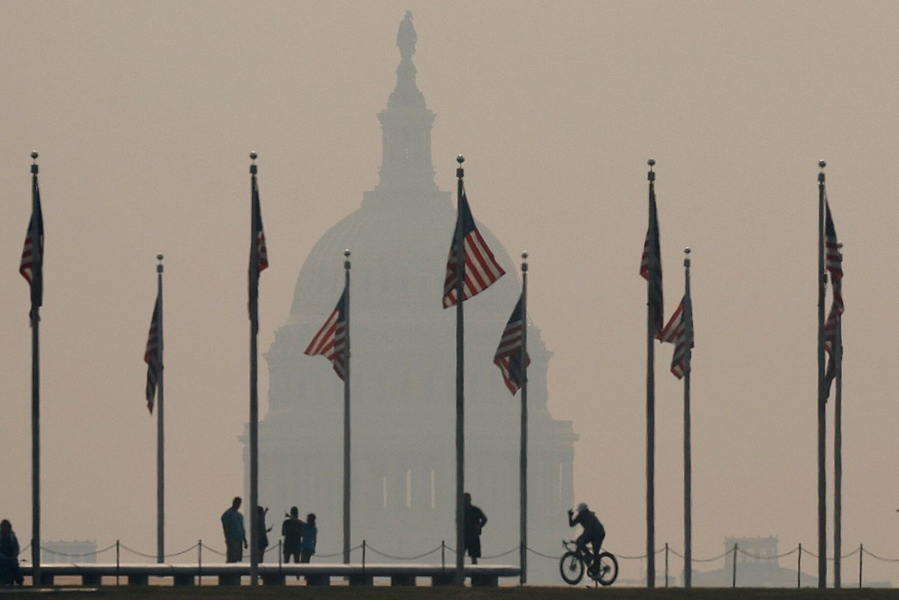 Tourists walk around the base of the Washington Monument as wildfire smoke casts a haze off the U.S. Capitol on the National Mall on Wednesday.