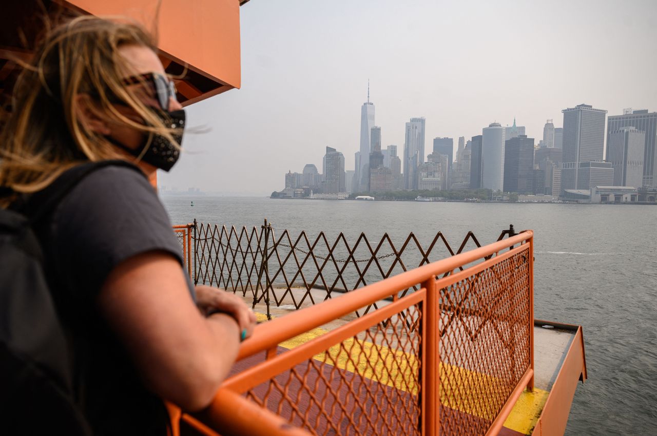 A passenger wearing a face mask rides the Staten Island Ferry past the Manhattan skyline during heavy smog in New York on Tuesday. 