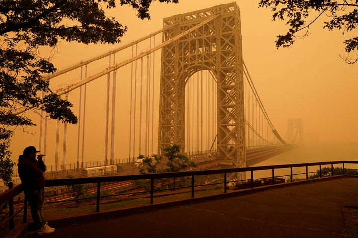 A man talks on his phone as he looks through the haze at the George Washington Bridge in Fort Lee, N.J., on June 7, 2023.