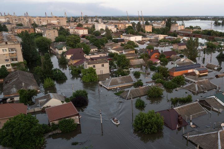 People ride on a rubber boat in a flooded neighborhood in Kherson, Ukraine, on June 7, 2023.