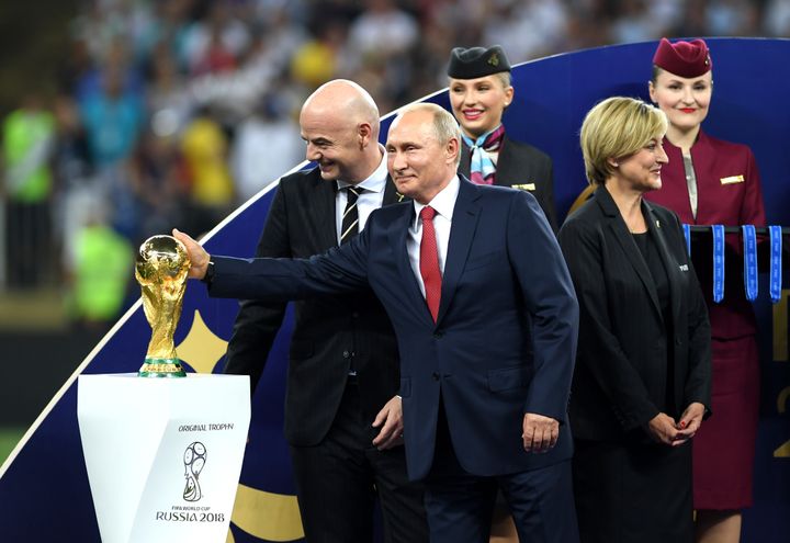 Russian President Vladimir Putin touches the World Cup trophy as FIFA President Gianni Infantino looks on during the 2018 FIFA World Cup Final between France and Croatia at Luzhniki Stadium in Moscow.