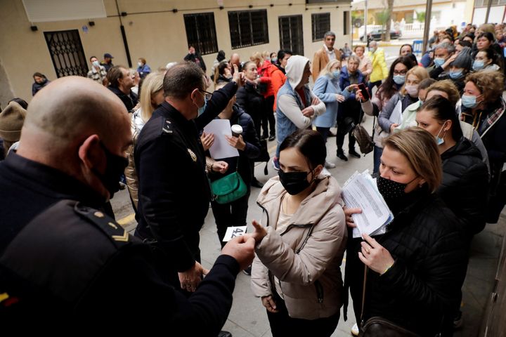 Η αστυνομία παραδίδει χαρτιά με την επιβεβαίωση για κλείσιμο ραντεβού σε Ουκρανούς πρόσφυγες, που κάνουν ουρά για να λάβουν ένα από τα 100 καθημερινά ραντεβού στο γραφείο τεκμηρίωσης της Ισπανίας, ώστε να υποβάλουν αίτηση για προσωρινή προστασία εγκεκριμένη από την Ευρωπαϊκή Ένωση που επιτρέπει τη διαμονή και την άδεια εργασίας, στην Torrevieja της Ισπανίας, 15 Μαρτίου 2022. REUTERS/Eva Manez