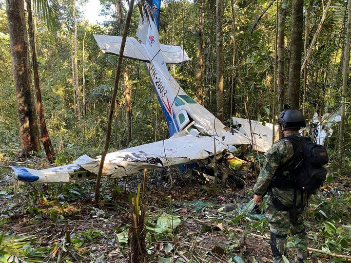 In this photo released by Colombia's Armed Forces Press Office, a soldier stands in front of the wreckage of a Cessna C206, May 18, 2023, that crashed in the jungle of Solano in the Caqueta state of Colombia.
