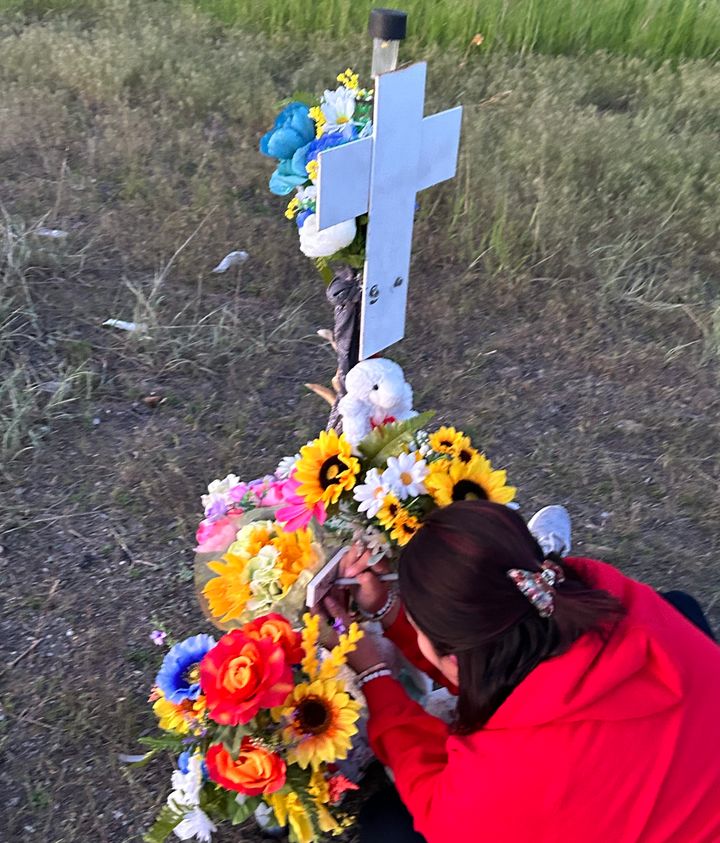Heavy Runner places flowers by a memorial cross for her daughter off the highway where she was killed