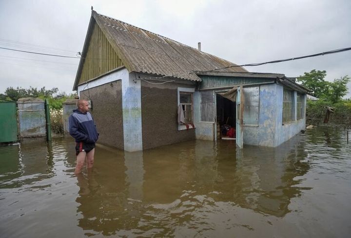 A local resident looks at his flooded building after the Nova Kakhovka dam breached, amid Russia's attack on Ukraine.