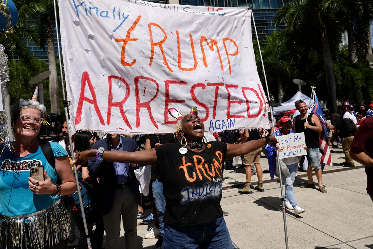 Nabine Seiler holds a sign that reads "Finally Trump Arrested Again" outside the Wilkie D. Ferguson Jr. courthouse.