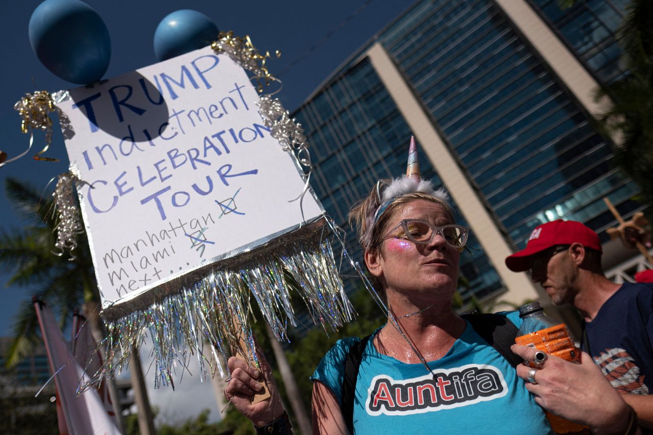 An anti-Trump demonstrator in front of the Miami courthouse holds a sign reading, "Trump Indictment Celebration Tour: Manhattan, Miami, Next...?"