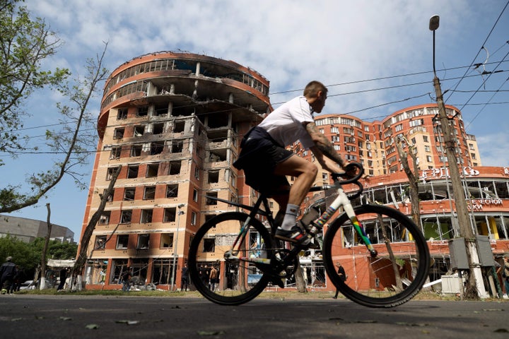 A man cycles past a commercial building, which was damaged after an overnight Russian strike in Odesa on June 14, 2023, amid the Russian invasion of Ukraine.