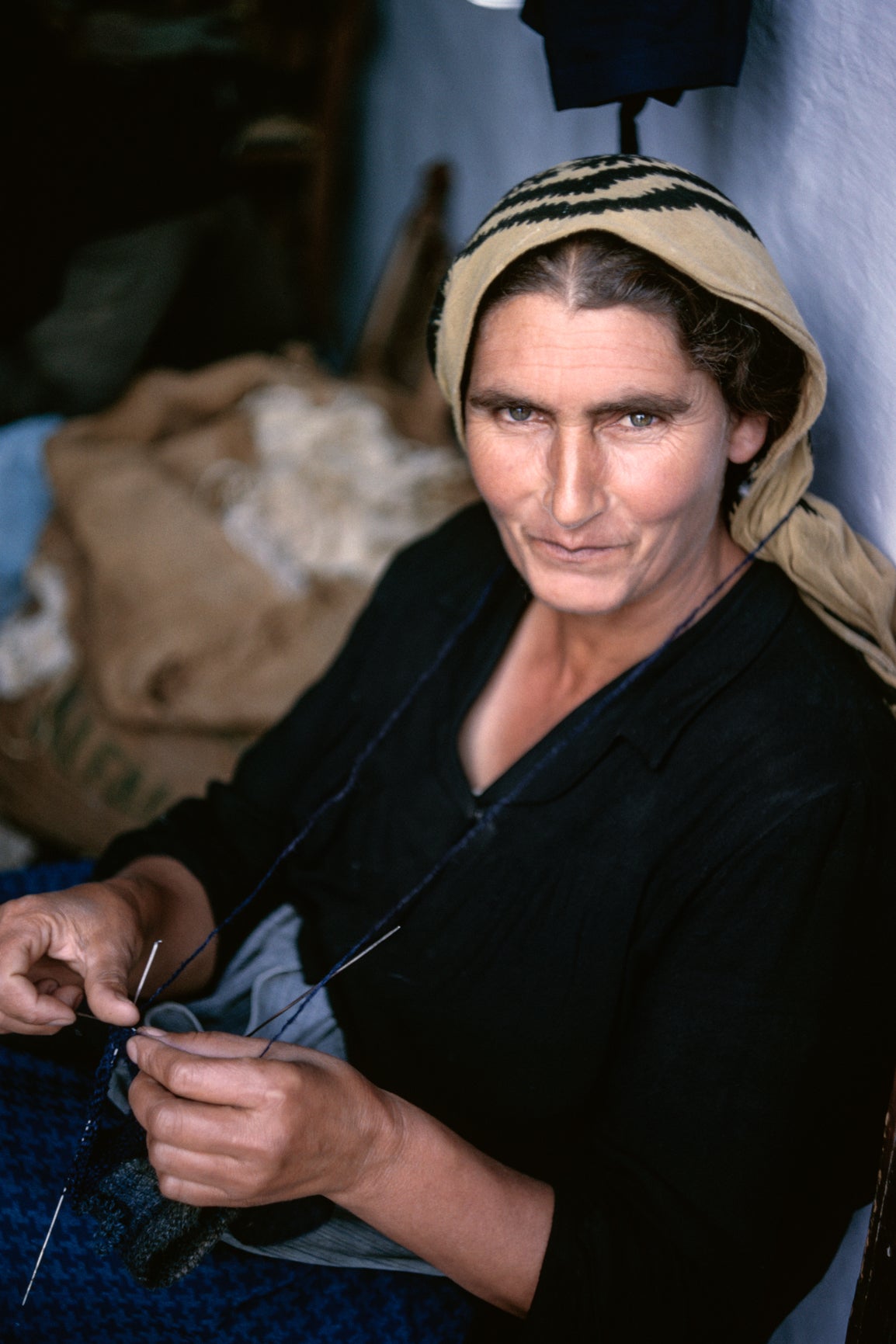 Σκύρος, 1957. Μια γυναίκα με το παραδοσιακό σκυριανό μαντίλι δεμένο στο κεφάλι σταματάτο πλέξιμο για να κοιτάξει τον φωτογράφο. Η ύφανση, το γνέσιμο, το κέντημα και το πλέξιμο ήταν καθημερινές απασχολήσεις στα μεταπολεμικά χρόνια