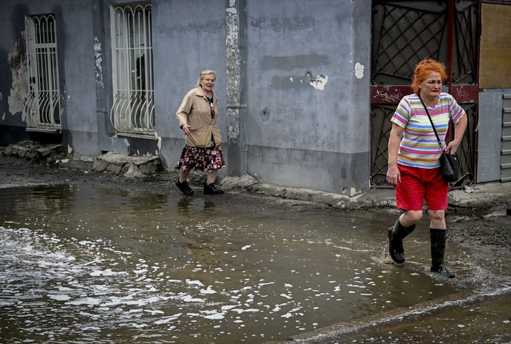 Women walk on a flooded street after the explosion at the Kakhovka Dam and Hydroelectric Power Plant in Kherson, Ukraine on June 14, 2023.