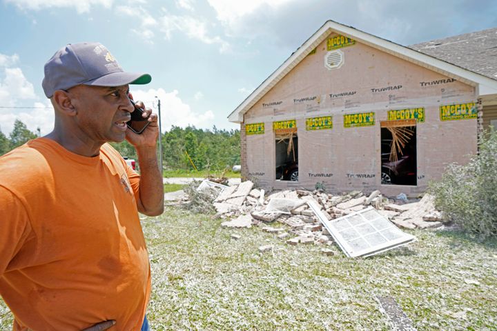 Lester Campbell takes a phone call as he stands before his home following an apparent tornado the night before that swept through Louin, Miss., Monday, June 19, 2023. The brick wall was blown away and the back roof of his house was heavily damaged. (AP Photo/Rogelio V. Solis)