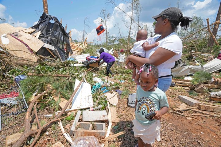 Dana Jackson holds her four month old daughter Brynlee Jackson, while she and daughter Genesis Jackson, three, watch relatives salvage personal items from a relative's mobile home that was demolished by an apparent Sunday night tornado that swept through Louin, Miss., Monday, June 19, 2023. Possible multiple tornadoes swept through Mississippi overnight, killing one and injuring nearly two dozen, officials said Monday. (AP Photo/Rogelio V. Solis)