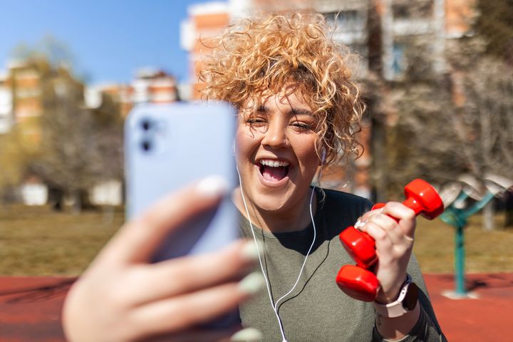 Young woman with headphones with dumbbells.
