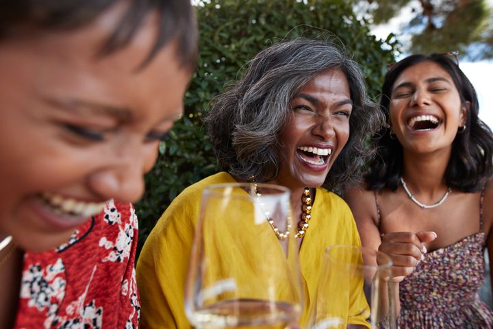 Female friends laughing with wineglasses in party during weekend
