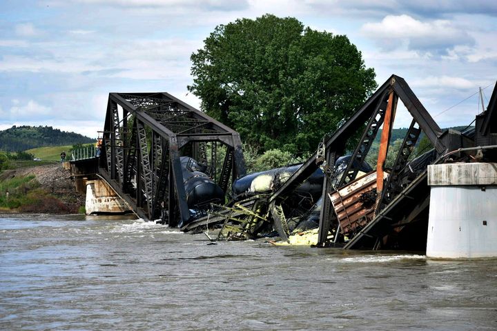 Several train cars are immersed in the Yellowstone River after a bridge collapse near Columbus, Mont., on Saturday, June 24, 2023. The bridge collapsed overnight, causing a train that was traveling over it to plunge into the water below. (AP Photo/Matthew Brown)