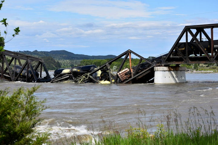 Several train cars are immersed in the Yellowstone River after a bridge collapse near Columbus, Mont., on Saturday, June 24, 2023. The bridge collapsed overnight, causing a train that was traveling over it to plunge into the water below. (AP Photo/Matthew Brown)